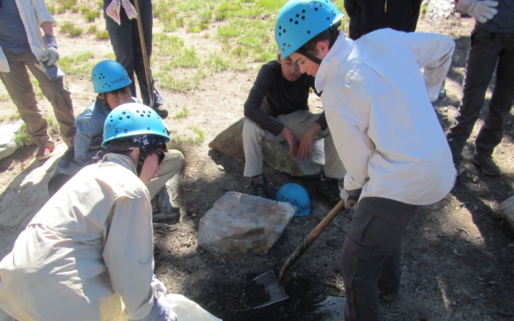 a group of students use shovels to dig during a service project with outward bound